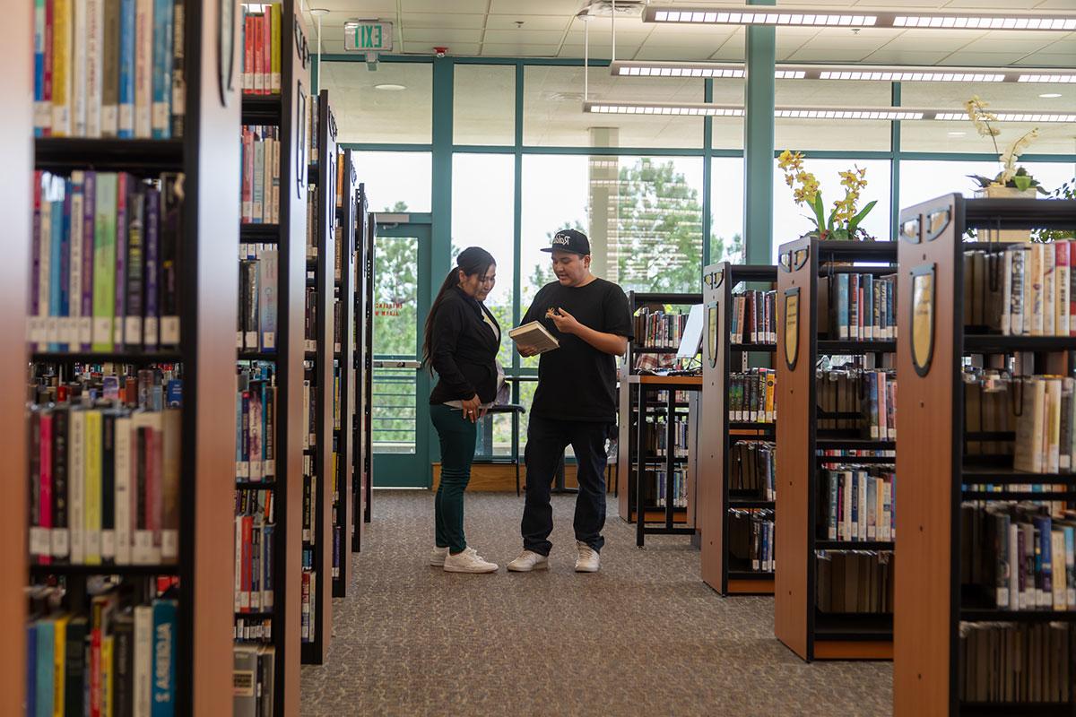 Two students in the SJC library looking at a book